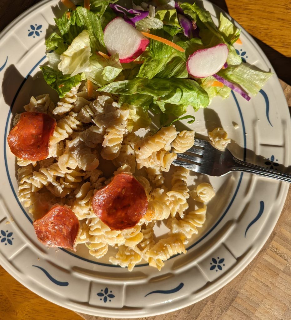 Serving suggestion of Pepperoni Alfredo Bake on dinner plate with tossed salad