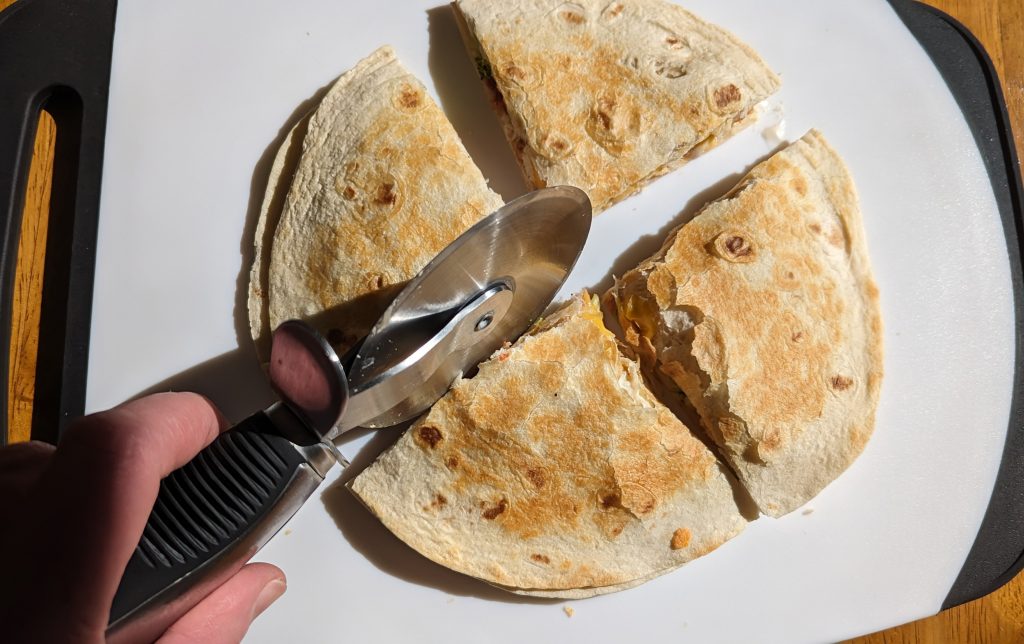 Cutting chicken bacon ranch quesadilla with pizza cutter