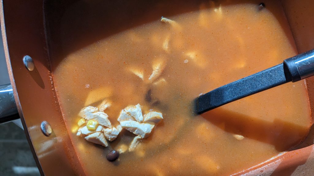 Adding chicken, corn and beans to the pot to make Creamy Chicken Enchilada Soup