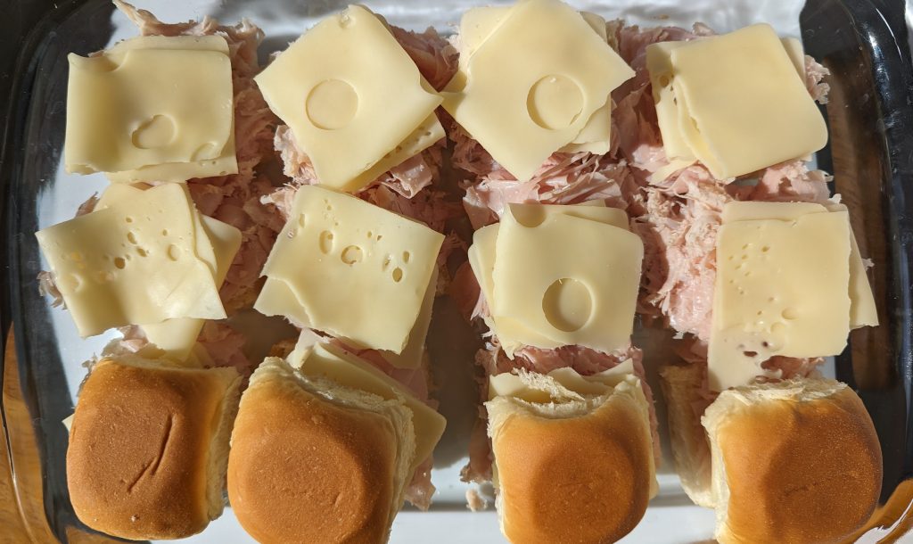 Ham and swiss cheese sliders being assembled in pan