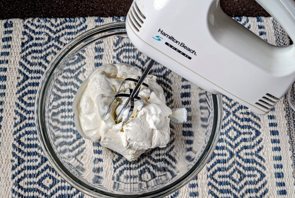 using a hand mixer to blend cream cheese and sour cream