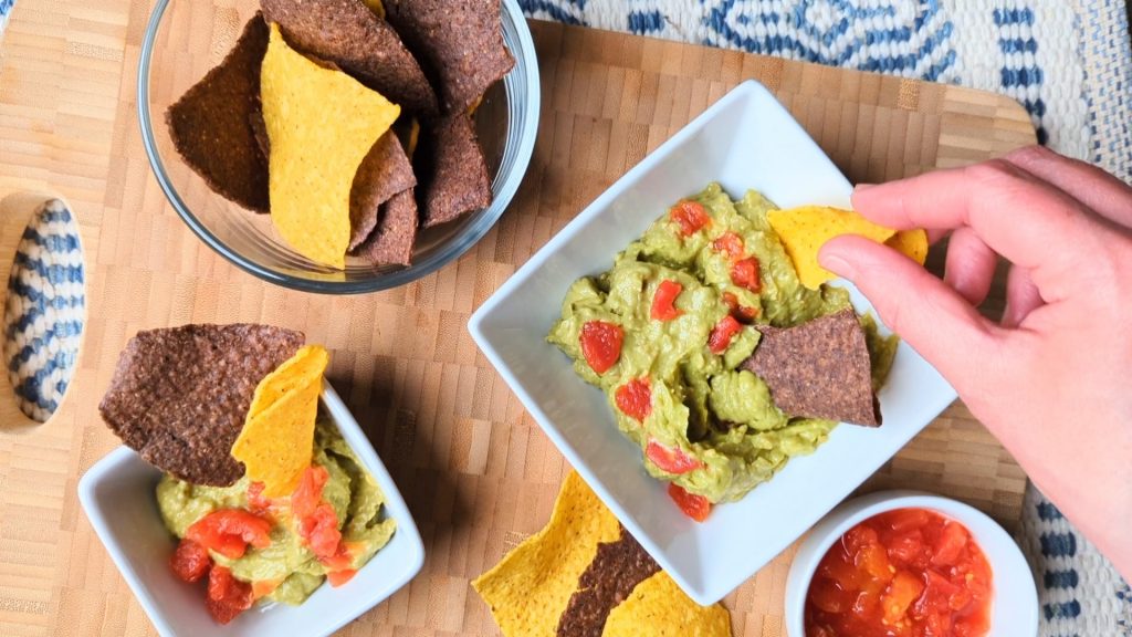 dipping a chip into easy cheesy guacamolr