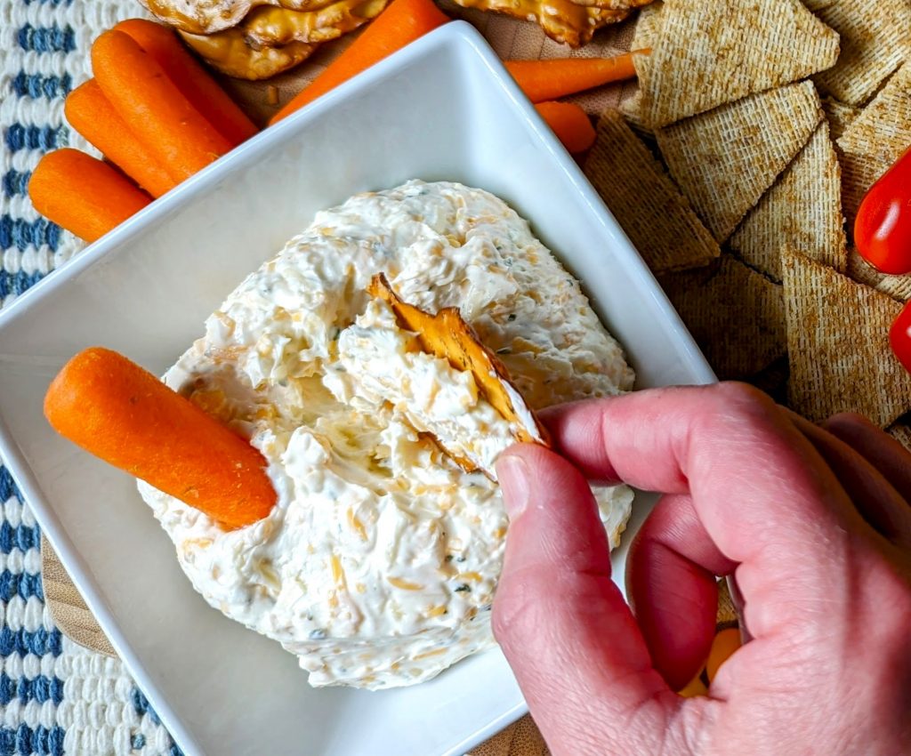 dipping pretzel in zesty ranch cheese ball