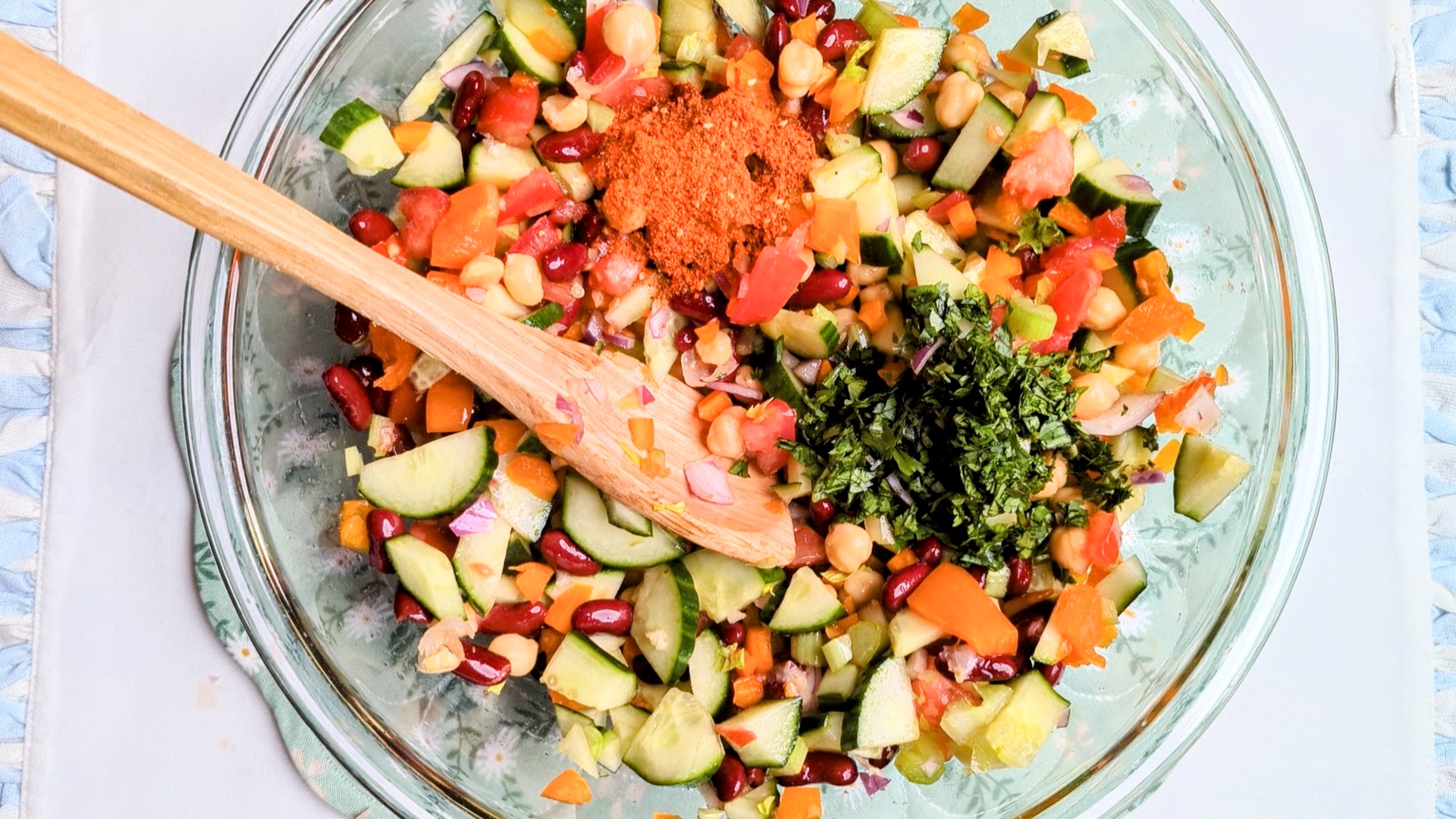 mediterannean bean salad being mixed in bowl