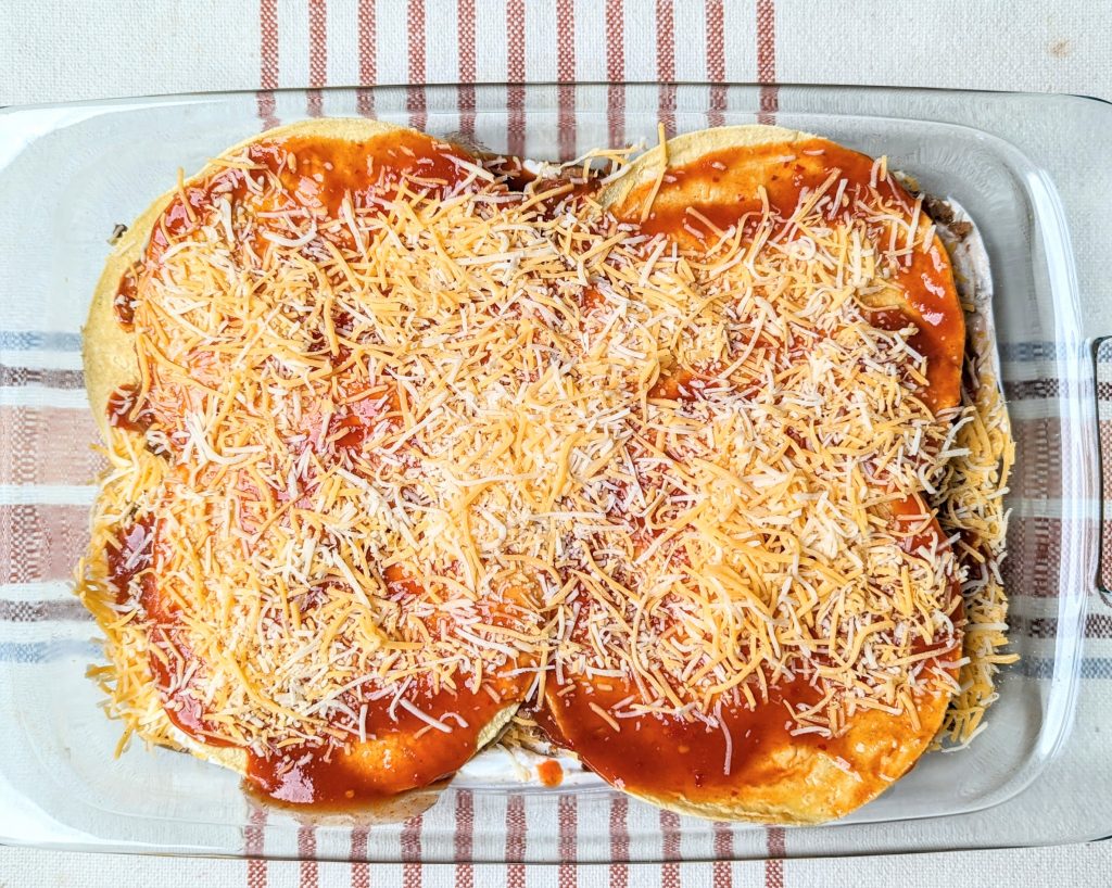 assembled three layer cheesy taco bake before baking