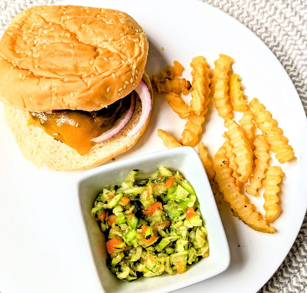 zucchini slaw on plate with bureger and fries