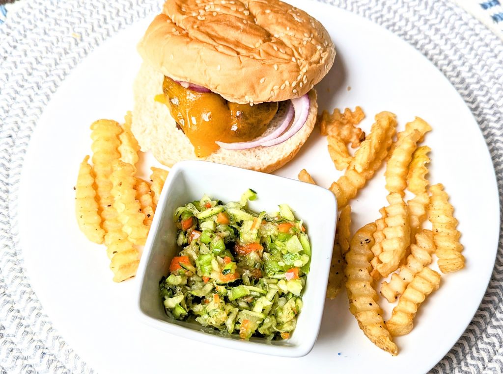 zucchini slaw on plate with burger and fries