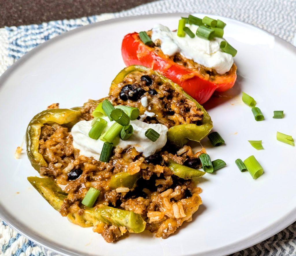 Mexican stuffed peppers on dish with sour cream and green onions