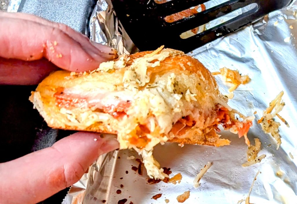 holding a cheesy pepperoni pizza slider