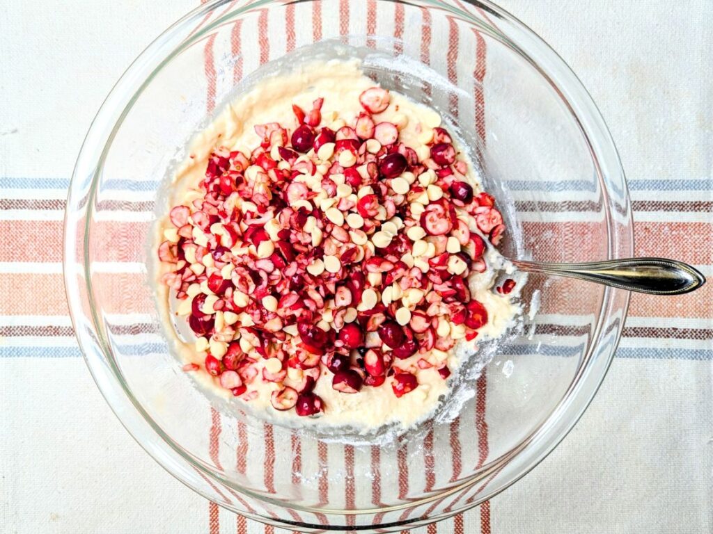 adding cranberries and chips to the bowl