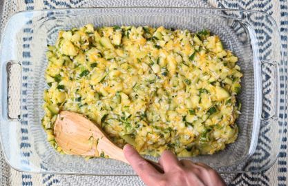 spreading cheesy rice zucchini casserole into pan