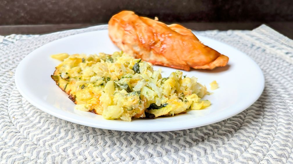 cheesy rice zucchini casserole on plate with chicken