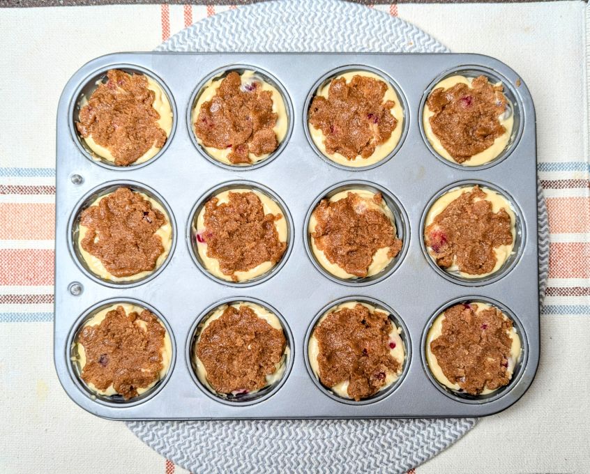 streusel placed on top of cranberry coffee cake muffins