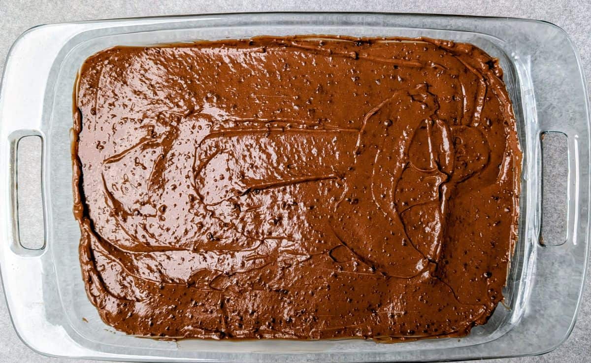 Spreading a smooth layer of chocolate pudding over the cream cheese filling.