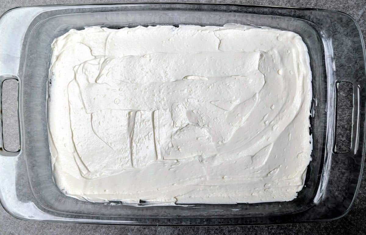 Spreading the creamy white cream cheese layer over the Oreo crust.
