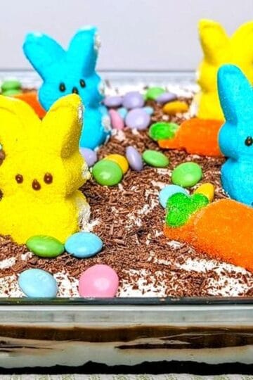 A finished Easter chocolate lasagna in a glass pan topped with yellow, blue, and orange marshmallow Peeps and chocolate shavings.