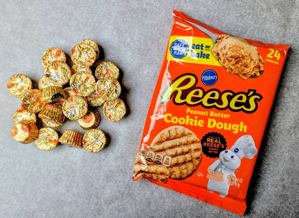 Ingredients for peanut butter cup cookies including a bag of Reese's cookie dough and a bowl of mini peanut butter cups.