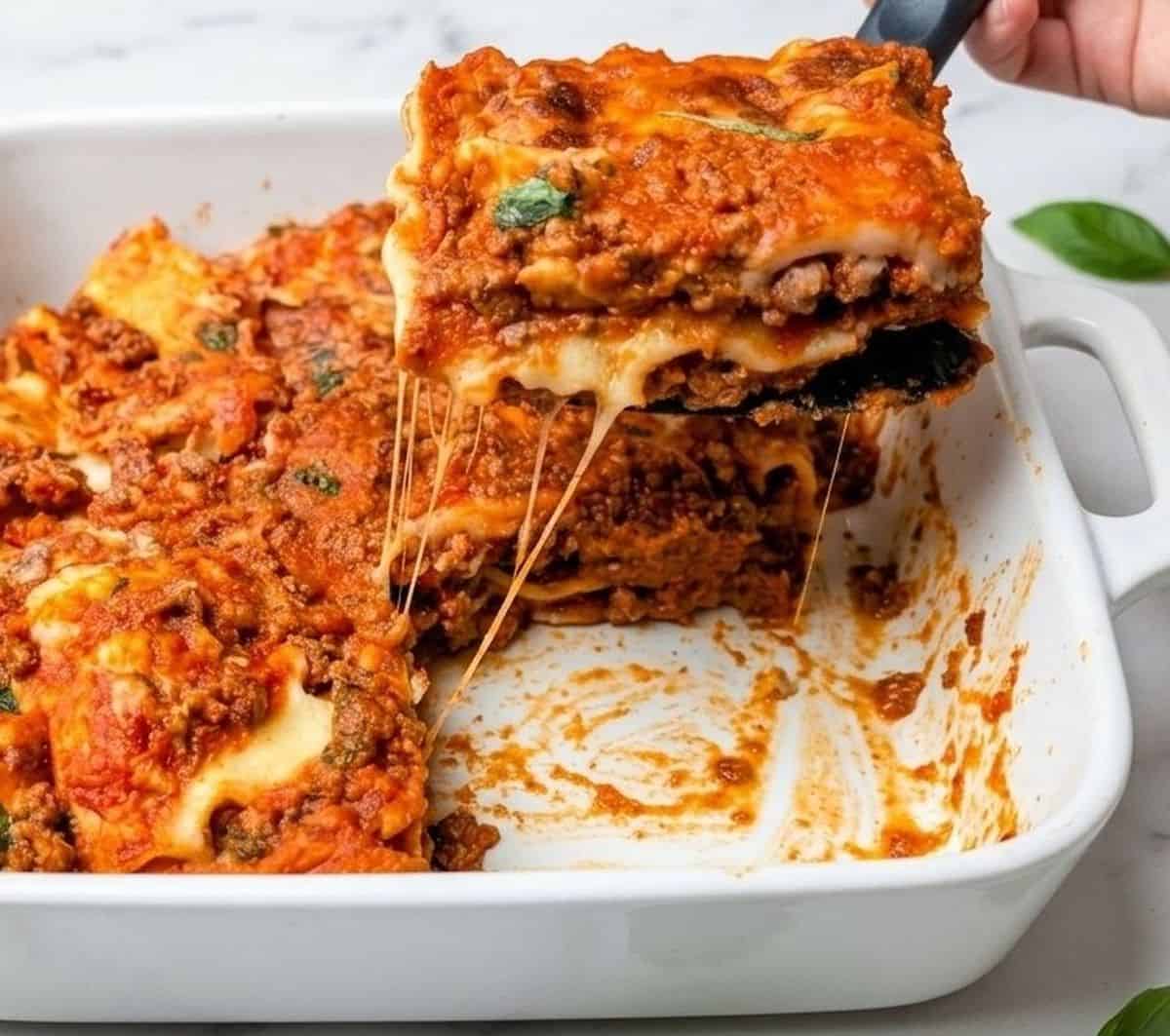 lazy lasagna serving being lifted out of casserole dish with cheese pull