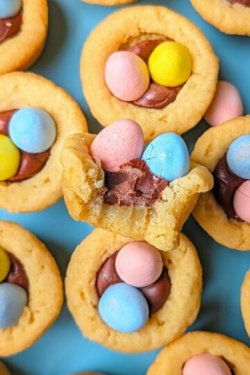 Easter mini egg cookie cups filled with frosting and topped with pastel candy eggs.