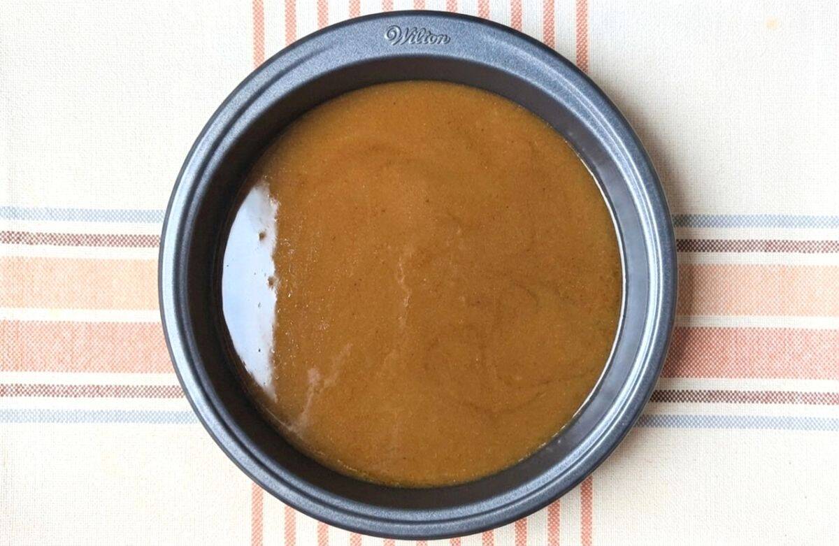 Spiced brown sugar and butter syrup melted in a round baking pan, ready for the peach upside-down cake topping.