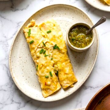 two chicken enchiladas with green sauce on serving plate