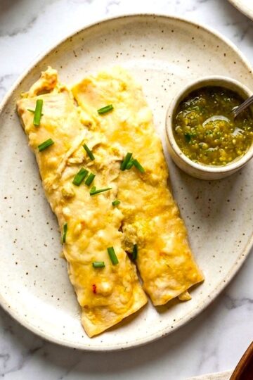 two chicken enchiladas with green sauce on serving plate