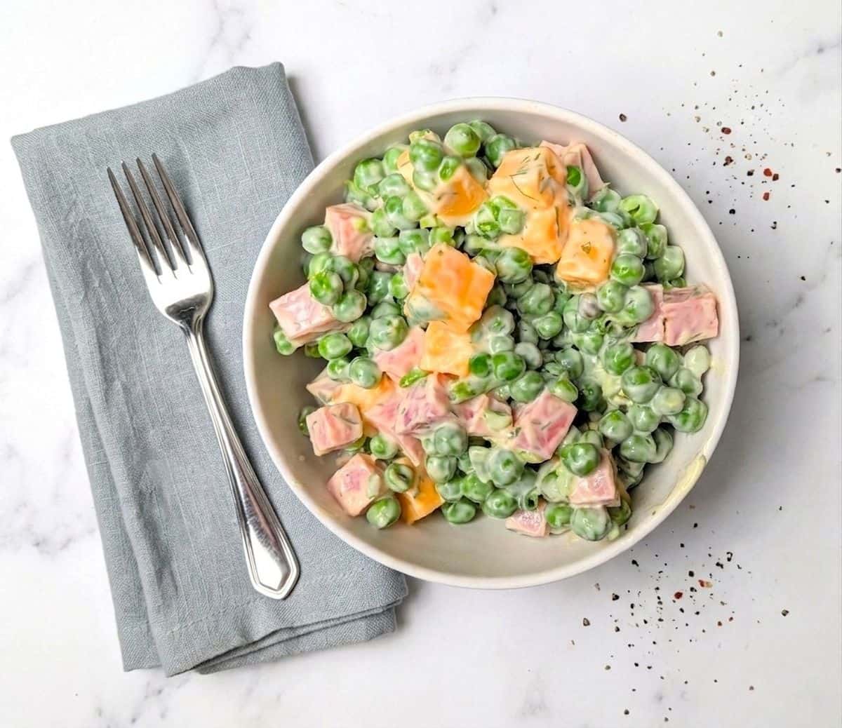 pea salad with ham and cheese in bowl with fork