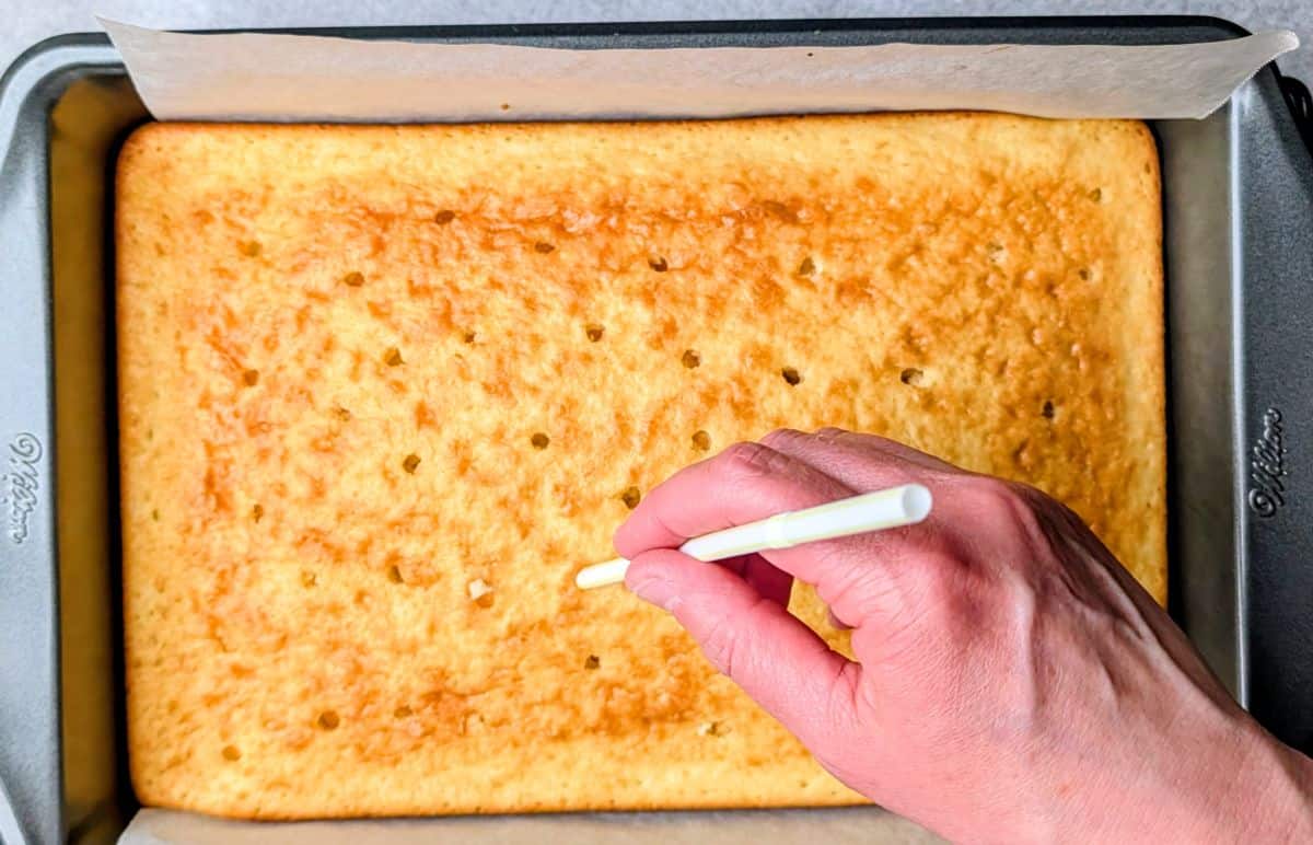 poking holes in cooled cake with straw