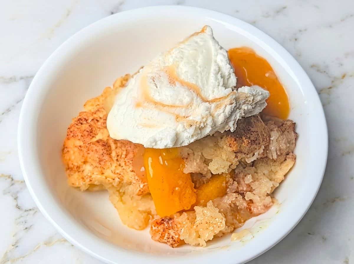easy peach cobbler in bowl with ice cream