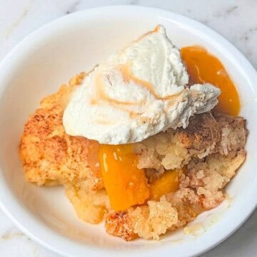 easy peach cobbler with canned peaches in serving bowl with ice cream