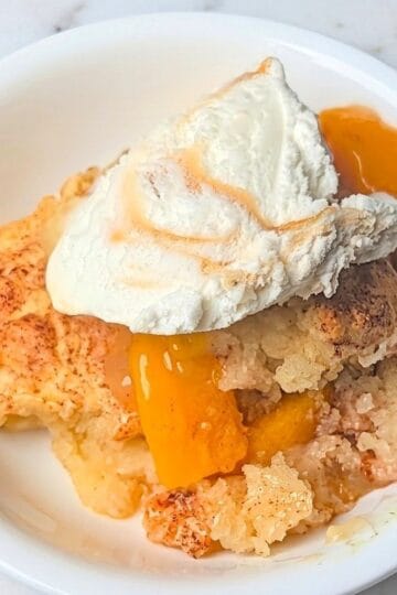 easy peach cobbler with canned peaches in serving bowl with ice cream