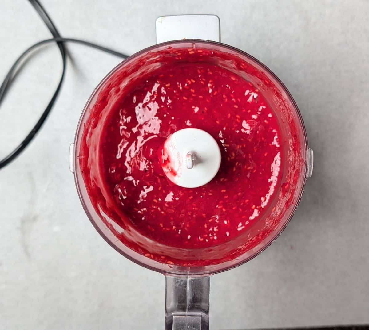Pureeing fresh red raspberries in a 7-cup food processor to make the jammy swirl for raspberry lemon cheesecake bars.