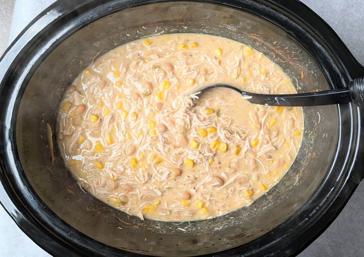A half block of cream cheese added to the chicken chili mixture in a slow cooker, a key step in making this crockpot cream cheese chicken chili.
