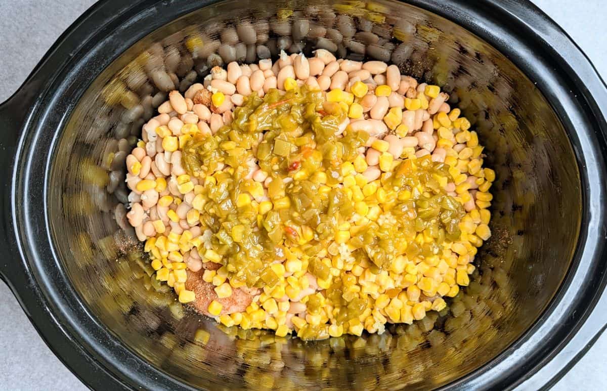 White beans, sweet corn, and green chilis added to the slow cooker for crockpot cream cheese chicken chili.