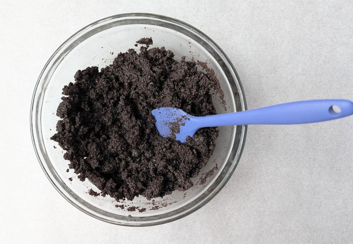 mixing crushed oreos and butter for crust
