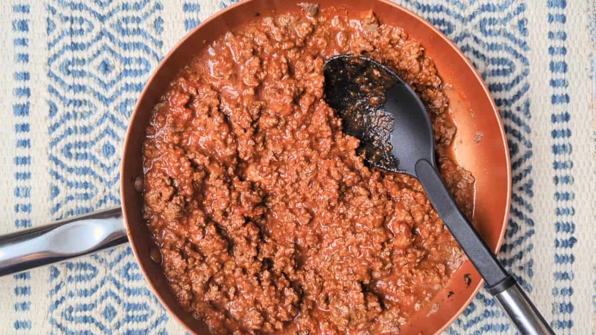Cooking the savory beef and tomato sauce mixture in a skillet for an easy eggplant casserole.