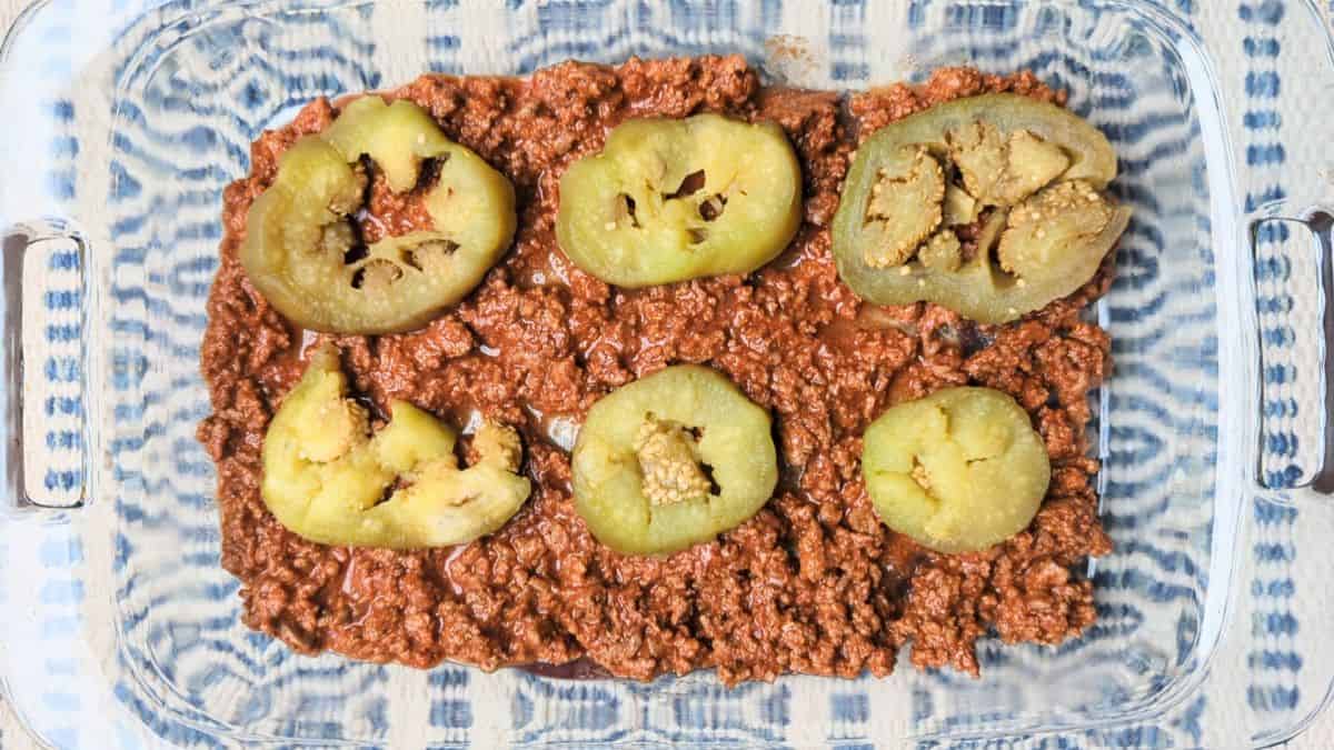 Layering the savory beef and tomato mixture over sliced eggplant in a baking dish to make an easy eggplant casserole.