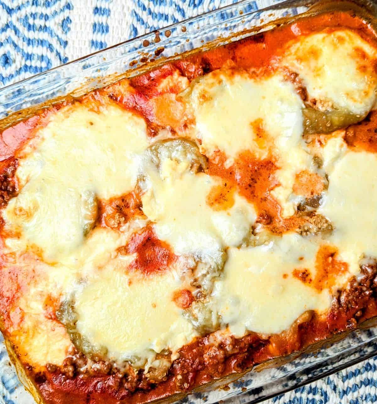 A close-up of a freshly baked easy eggplant casserole showing melted cheese and meat sauce in a baking dish. (