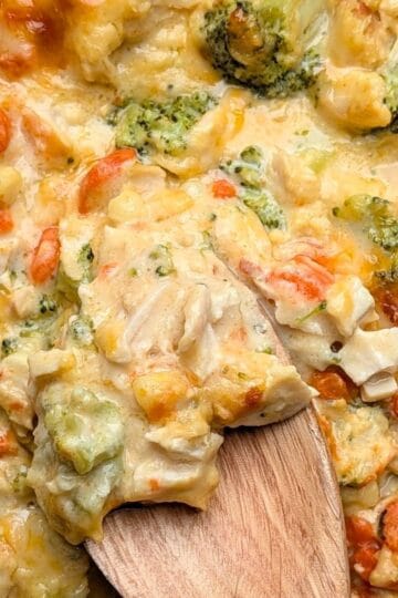 cheesy chicken broccoli casserole being lifted out of dish to serve
