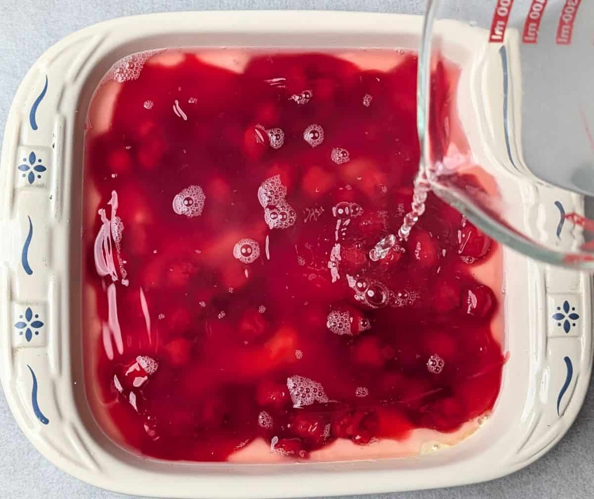 pouring boiling water and lemon juice on top of the cake before baking