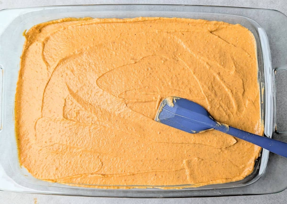 The third layer of a pumpkin lush recipe, showing a smooth pumpkin mixture spread evenly over the cream cheese layer.