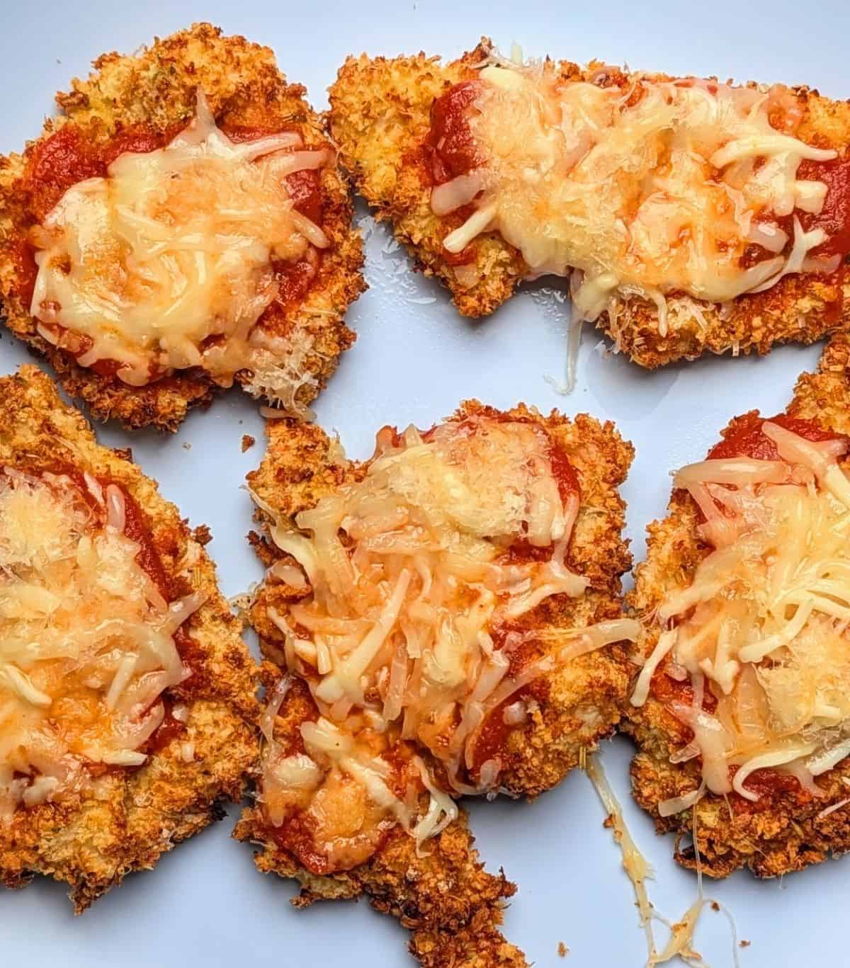 Breaded chicken cutlets topped with marinara sauce and melted cheese, the final step for healthy chicken parmesan.