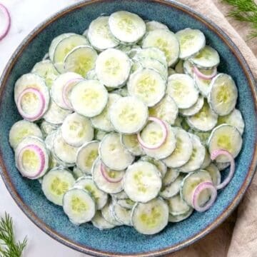 Creamy cucumber sour cream salad with fresh dill and red onions in a serving bowl.