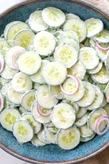 Creamy cucumber sour cream salad with fresh dill and red onions in a serving bowl.