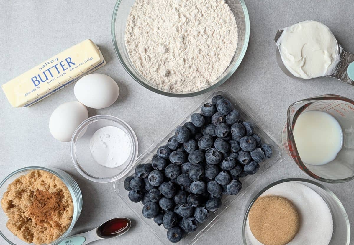 Ingredients gathered for making homemade Greek yogurt blueberry muffins, including flour, butter, eggs, and fresh blueberries.