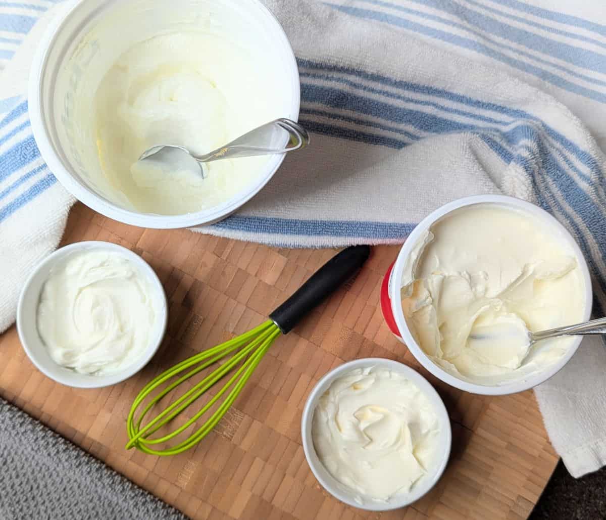 Side-by-side comparison of Greek yogurt and sour cream in small white bowls next to their containers.