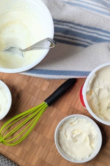Side-by-side comparison of Greek yogurt and sour cream in small white bowls next to their containers.