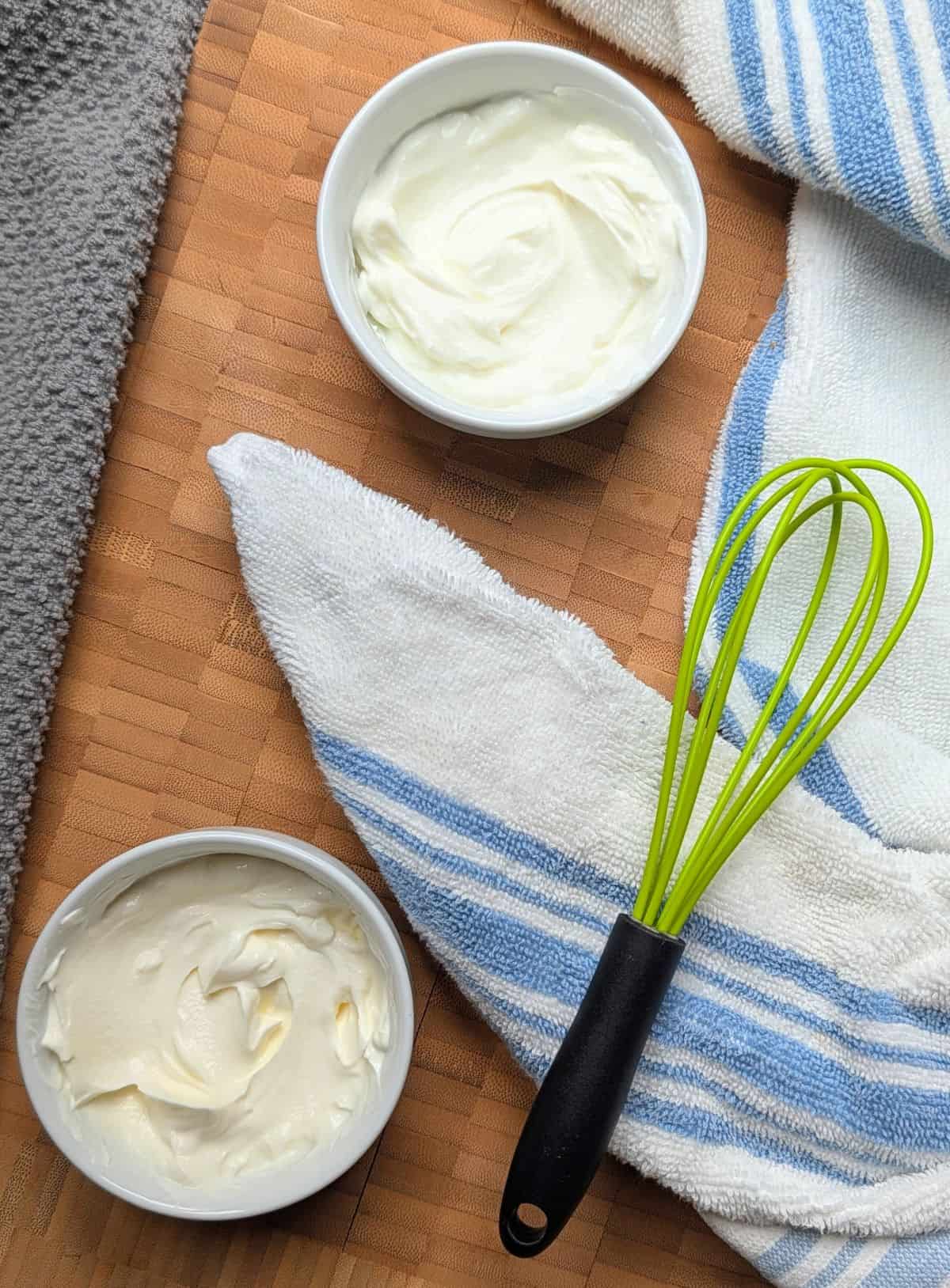 Overhead view of mixing Greek yogurt and sour cream together in a glass bowl to compare their textures.