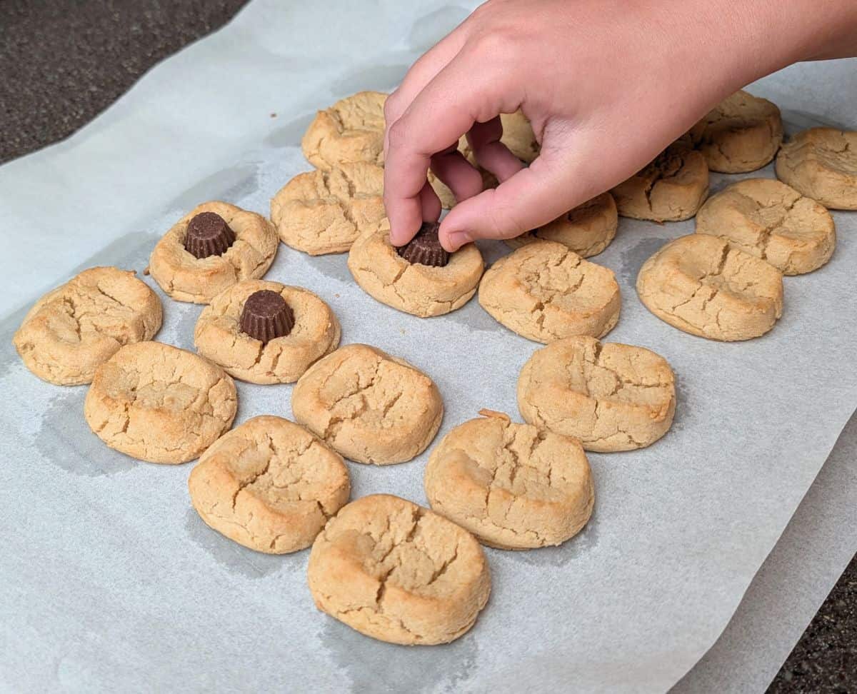 pressing peanut butter cups on baked cookies