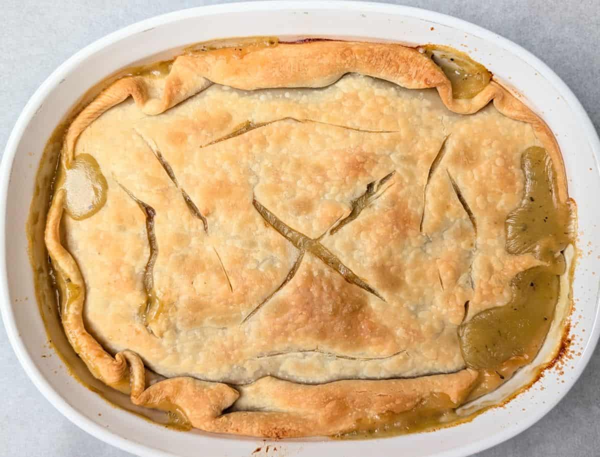 A freshly baked healthy chicken pot pie in a round casserole dish, featuring a golden brown pie crust with vent slits on top.
